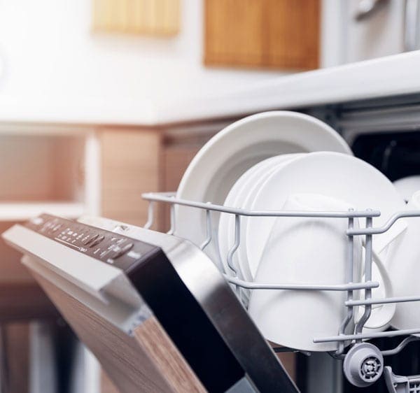 A dishwasher open showing clean white dishes